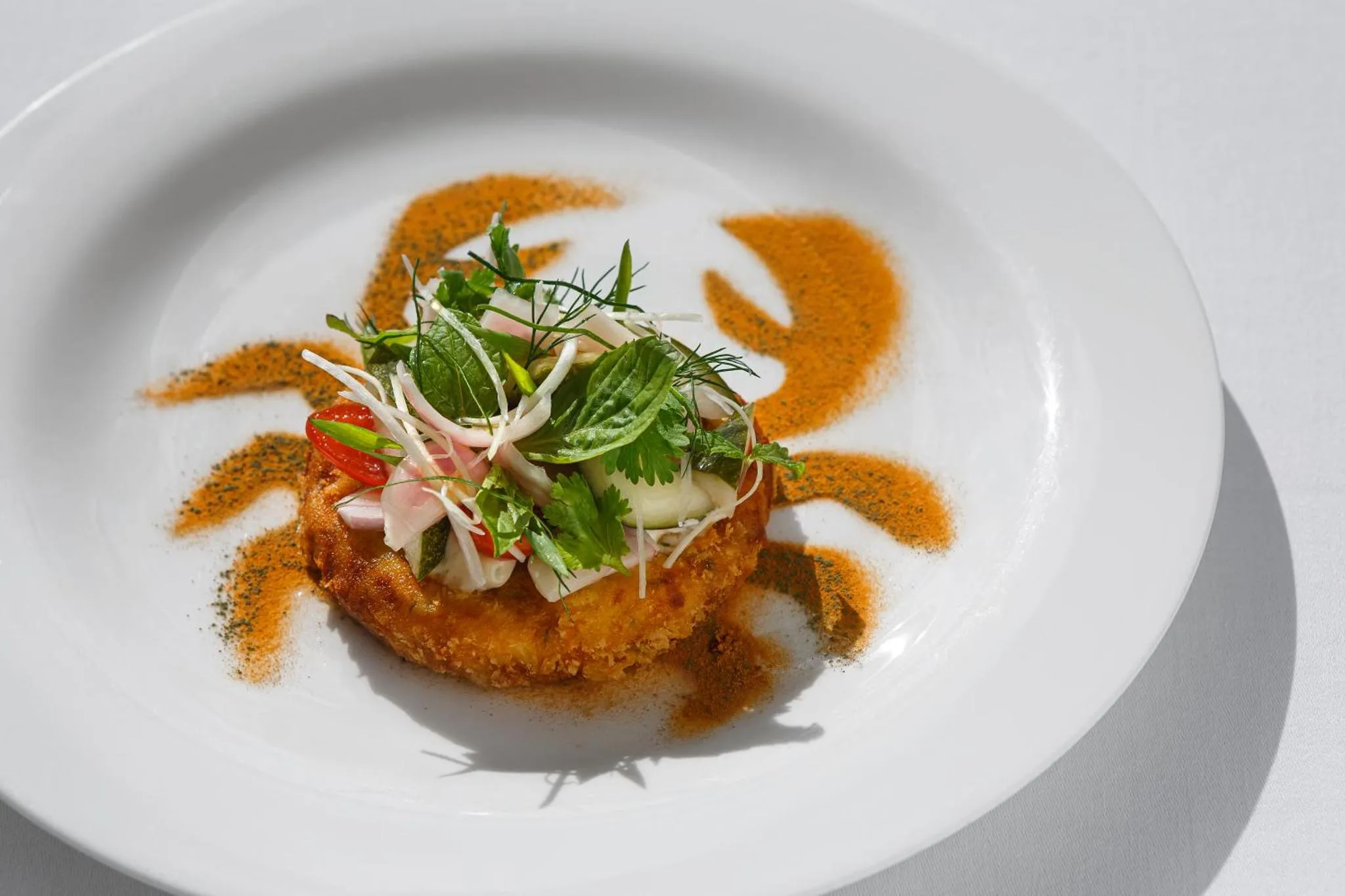 Assiette décorée d'une préparation culinaire à base de poisson et de légumes.
