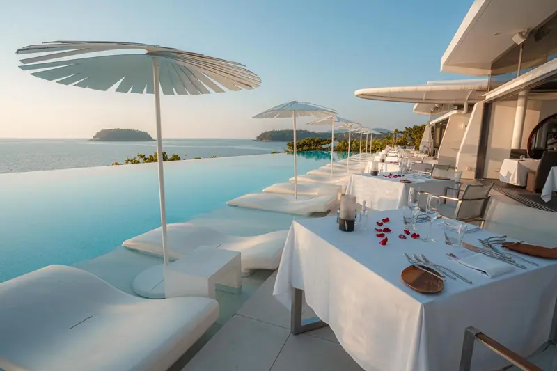 Tables dressées en bord de piscine avec vue sur la mer.