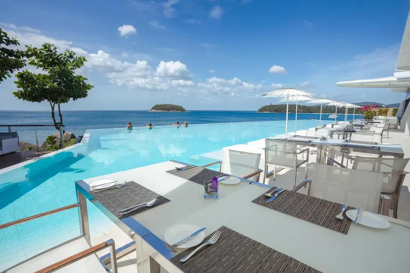 Tables dressées au bord d'une piscine à débordement avec vue sur la mer.