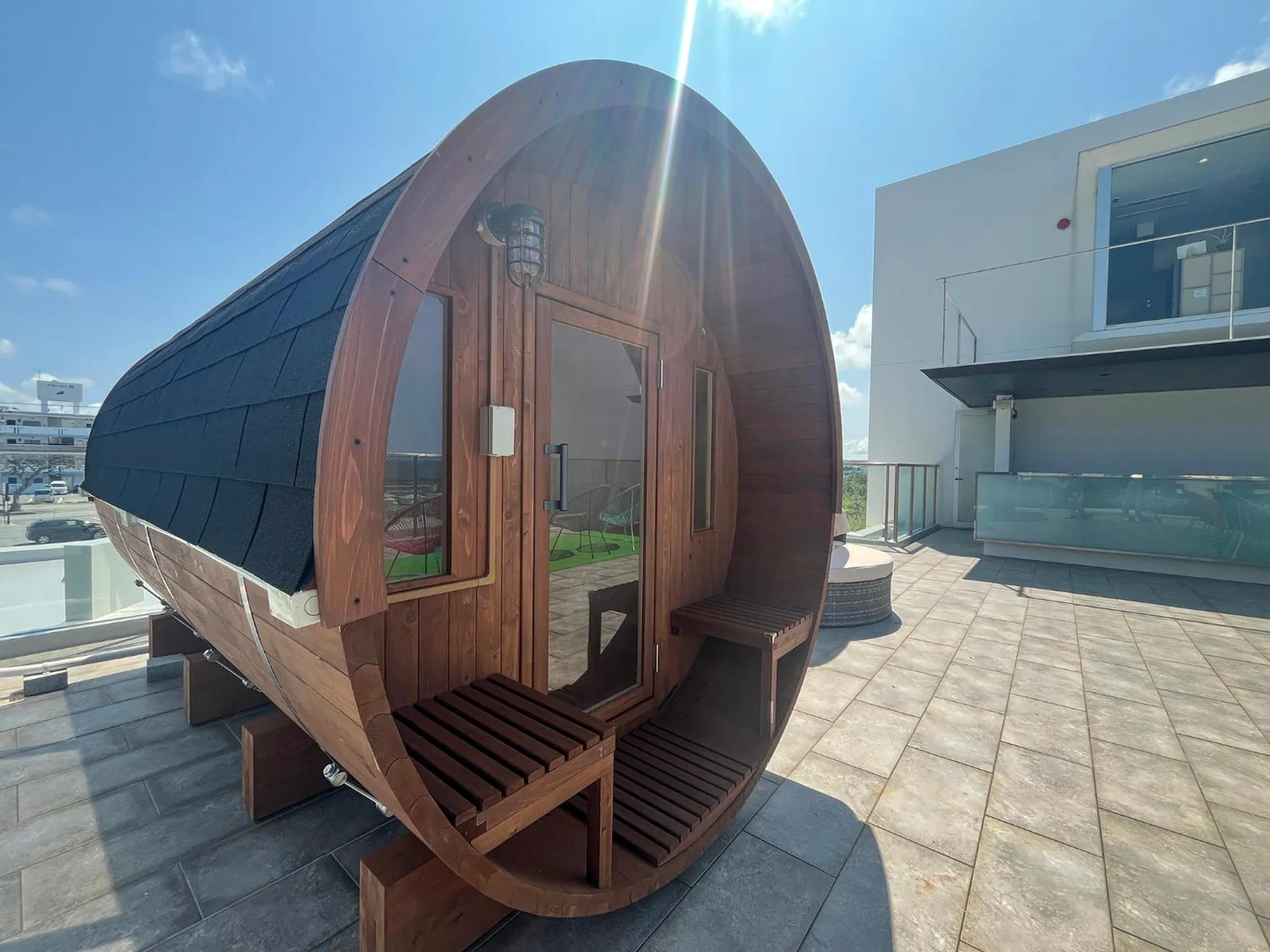 Une structure en bois de forme cylindrique repose sur une terrasse pavée.