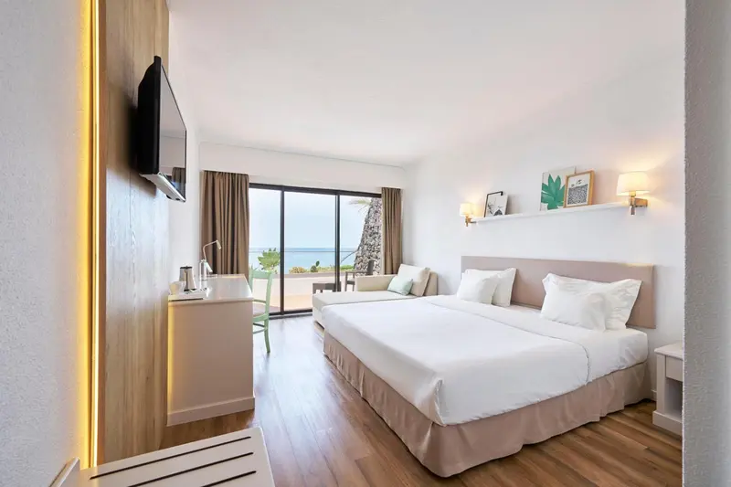 Chambre lumineuse avec un grand lit et vue sur la mer.