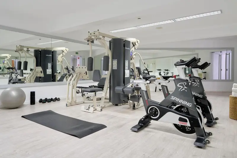 Une salle de sport lumineuse avec des équipements de fitness et des miroirs.