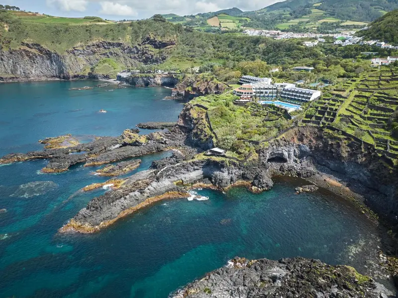 Vue aérienne d'une côte rocheuse avec un établissement hôtelier et des piscines.