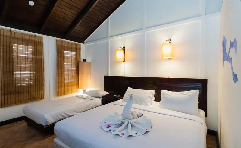 Une chambre lumineuse avec deux lits simples décorés de serviettes.