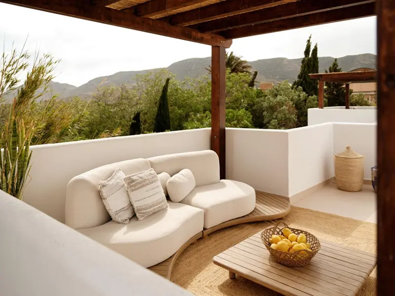 Espace de détente extérieur avec canapé blanc et table basse en bois.