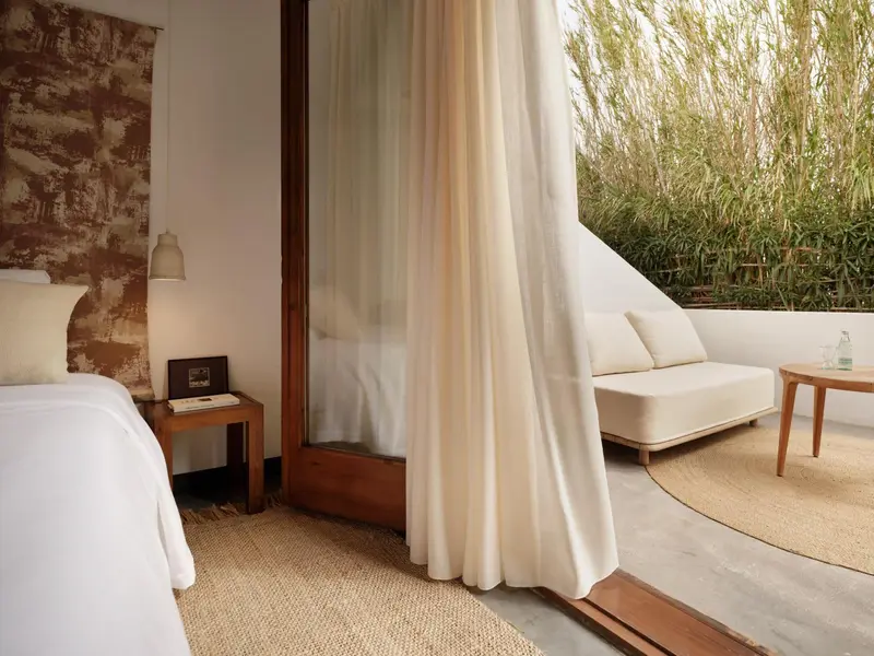 Une chambre lumineuse avec un lit blanc et un coin salon.
