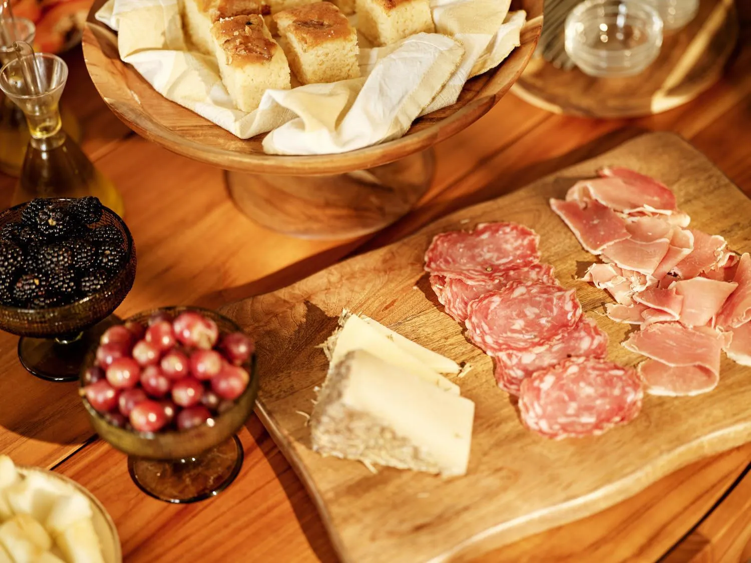 Assortiment de charcuterie, fromages et olives présentés sur une table en bois.