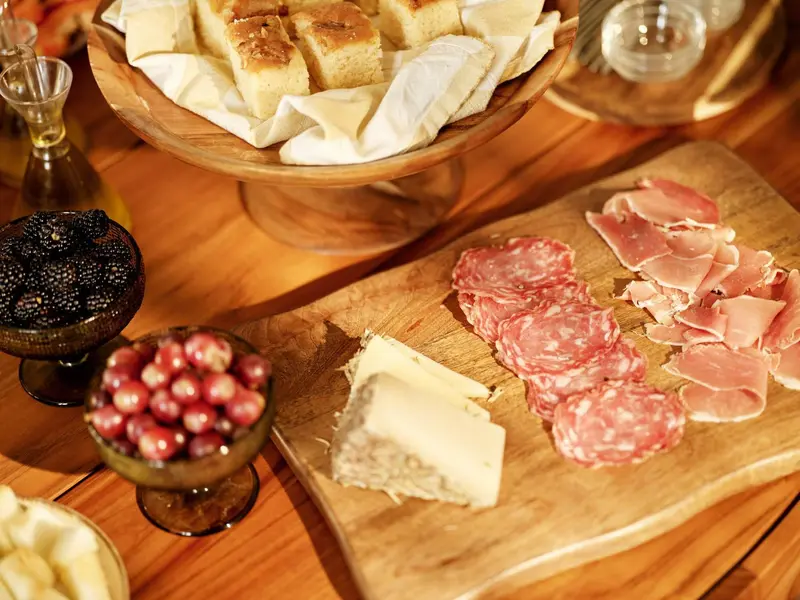 Assortiment de charcuterie, fromages et olives présentés sur une table en bois.
