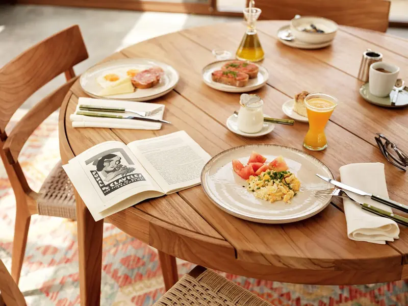 Une table en bois est dressée pour un repas avec des assiettes de nourriture et des boissons.