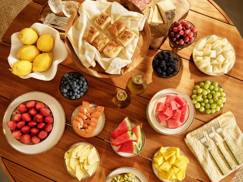 Une table en bois est garnie de fruits frais, de pâtisseries et de boissons.