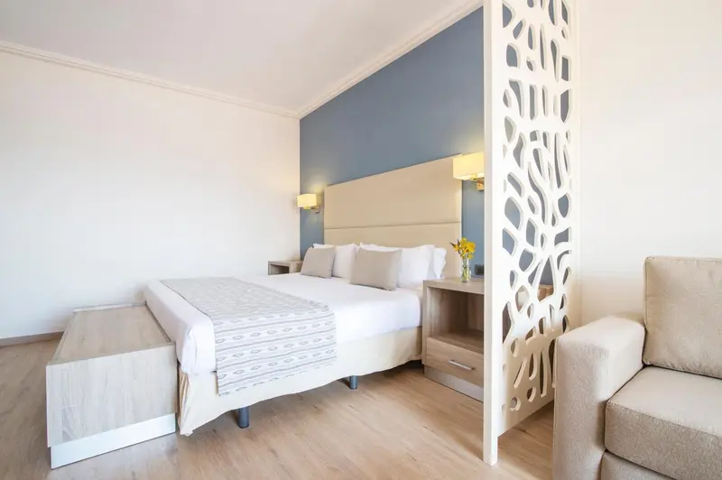 Une chambre lumineuse avec un grand lit et un coin salon.