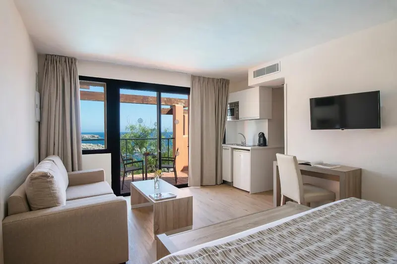 Espace de vie lumineux avec canapé, cuisine équipée et vue sur la mer.