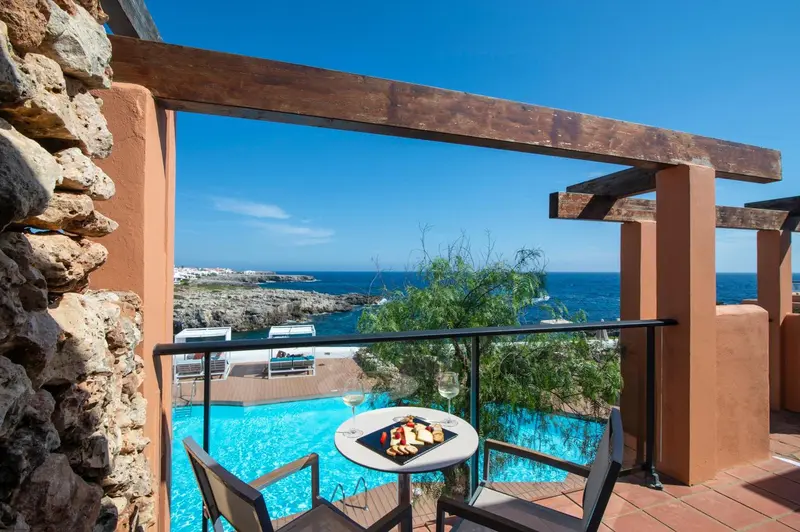 Terrasse avec table basse et vue sur la mer et une piscine.