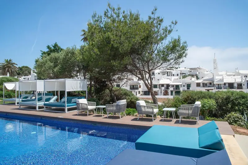 Transats bleus et mobilier de jardin au bord d'une piscine ensoleillée.