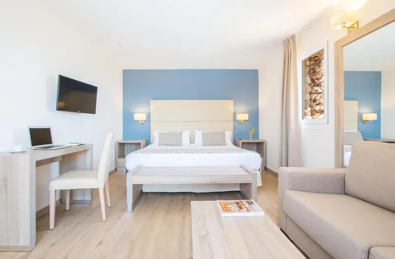 Une chambre lumineuse avec un grand lit et un coin salon.