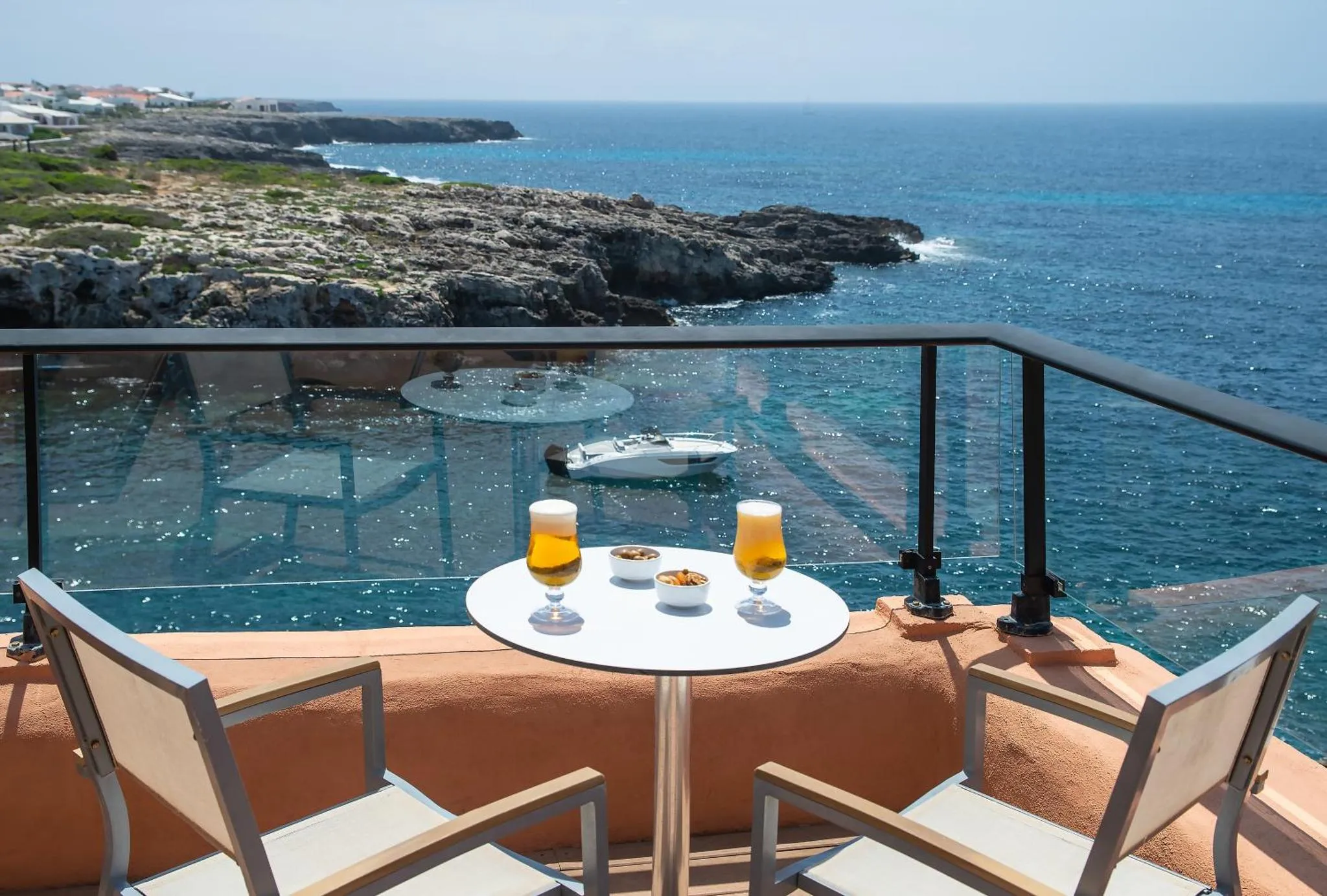 Une table avec des verres et des assiettes sur une terrasse avec vue sur la mer.