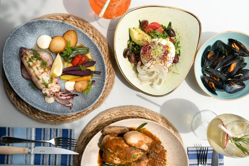 Assiettes garnies de fruits de mer et de légumes frais, accompagnées de boissons colorées.