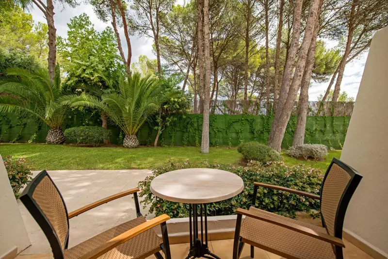Terrasse avec mobilier de jardin donnant sur un espace vert arboré.