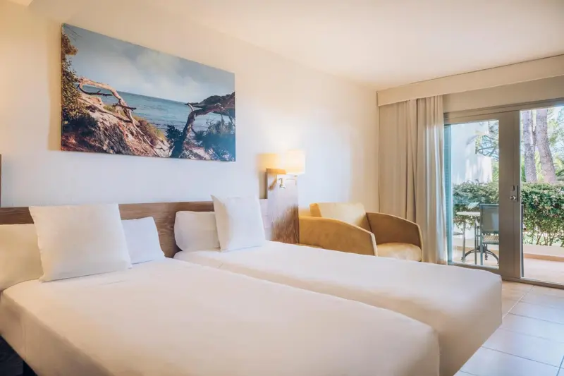 Une chambre lumineuse avec un grand lit et un fauteuil.