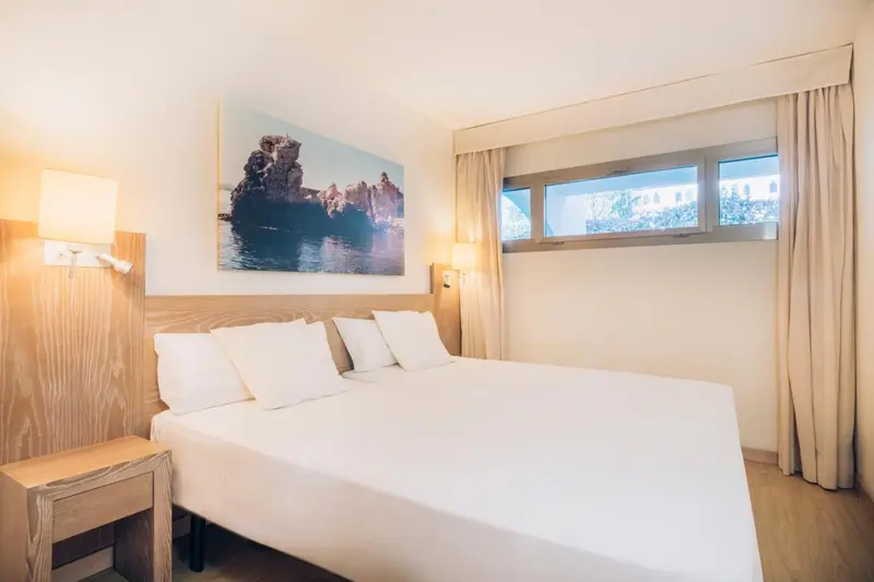 Une chambre lumineuse avec un grand lit et une décoration murale.