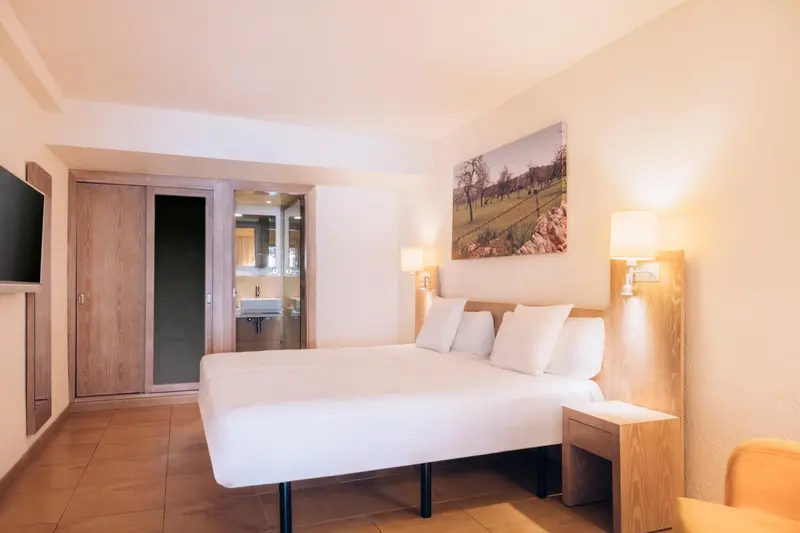 Une chambre lumineuse avec un grand lit et un accès à une salle de bain.