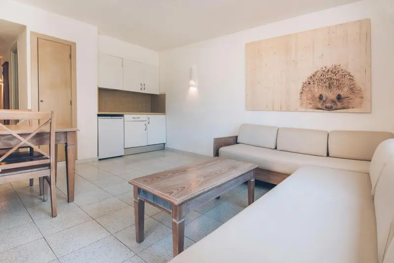 Espace de vie lumineux avec canapé, table basse et coin repas.