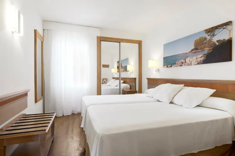 Une chambre lumineuse avec un grand lit et un tableau représentant un paysage marin.