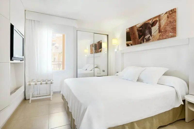 Une chambre lumineuse avec un grand lit et un tableau mural.