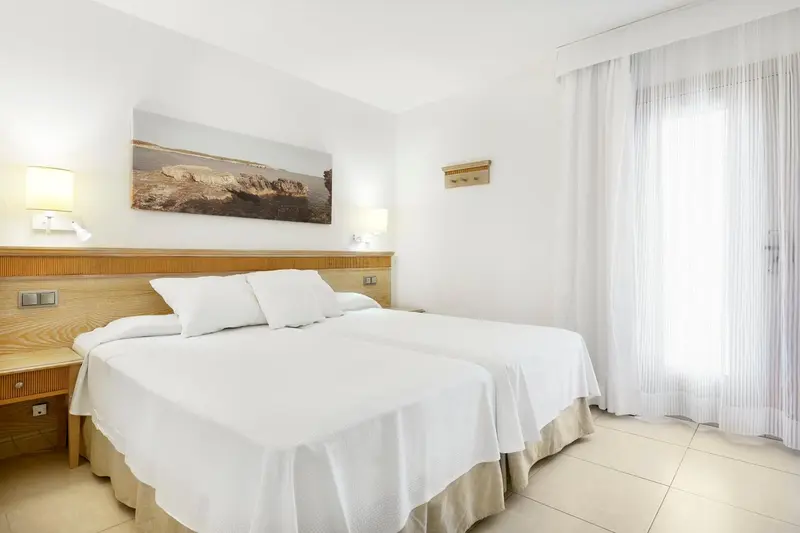 Une chambre lumineuse avec un grand lit recouvert de draps blancs.
