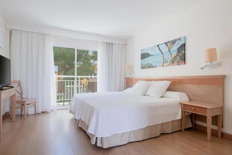 Une chambre lumineuse avec un grand lit et un accès à un balcon.