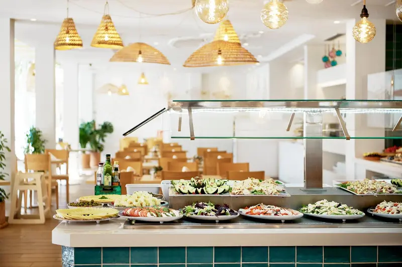 Un buffet propose une variété de salades et de plats préparés dans un espace lumineux et décoré.
