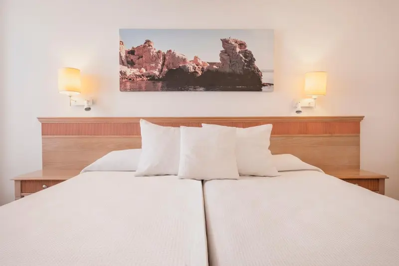 Une chambre lumineuse avec un grand lit et une décoration murale.