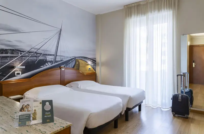 Une chambre d'hôtel lumineuse avec deux lits simples et un grand décor mural.