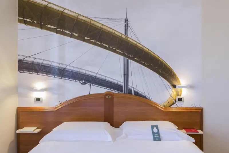 Un lit double avec une tête de lit en bois devant un mur décoré d'une image de pont.