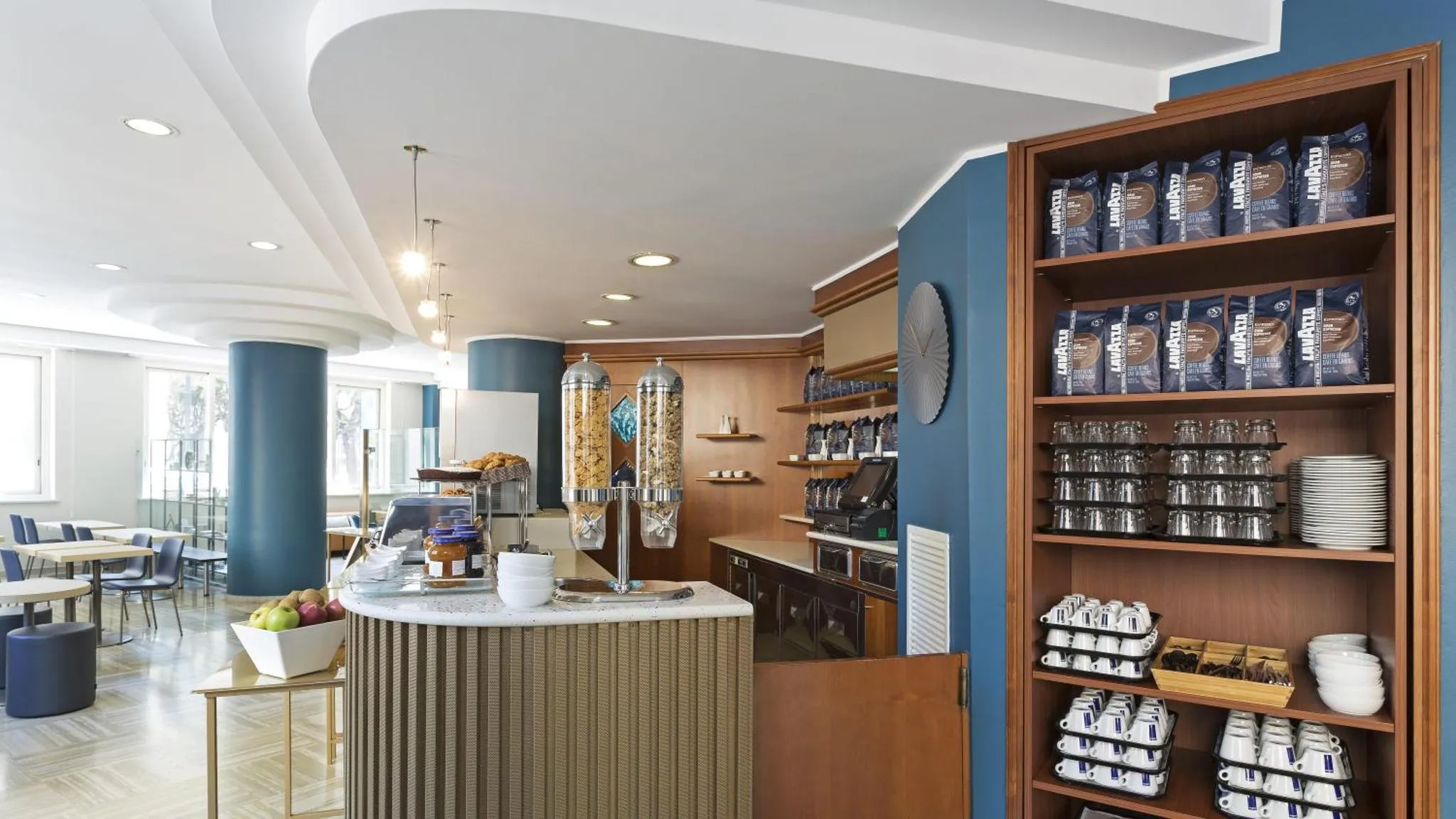 Un comptoir de service propose des boissons chaudes et des pâtisseries dans un espace lumineux et moderne.