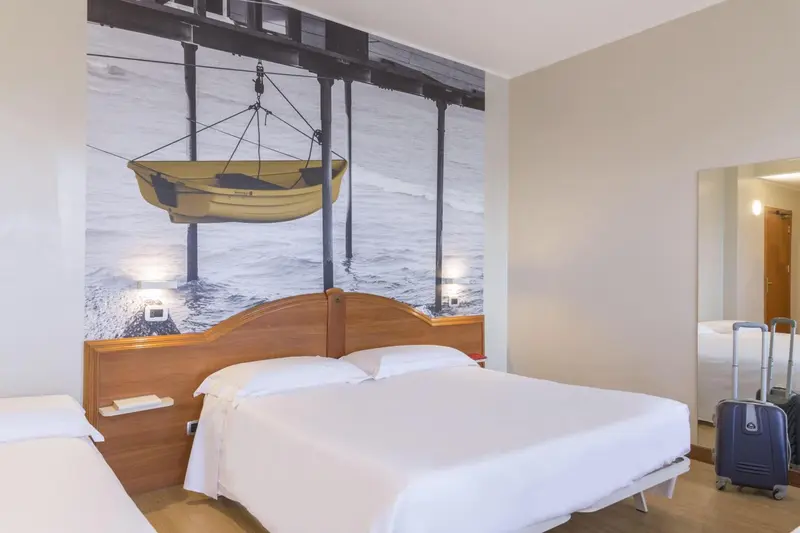 Une chambre lumineuse avec un grand lit et une décoration murale représentant un bateau.