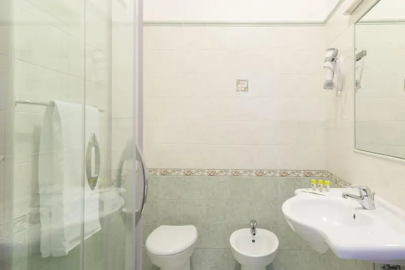 Une salle de bain claire avec douche, lavabo et WC.