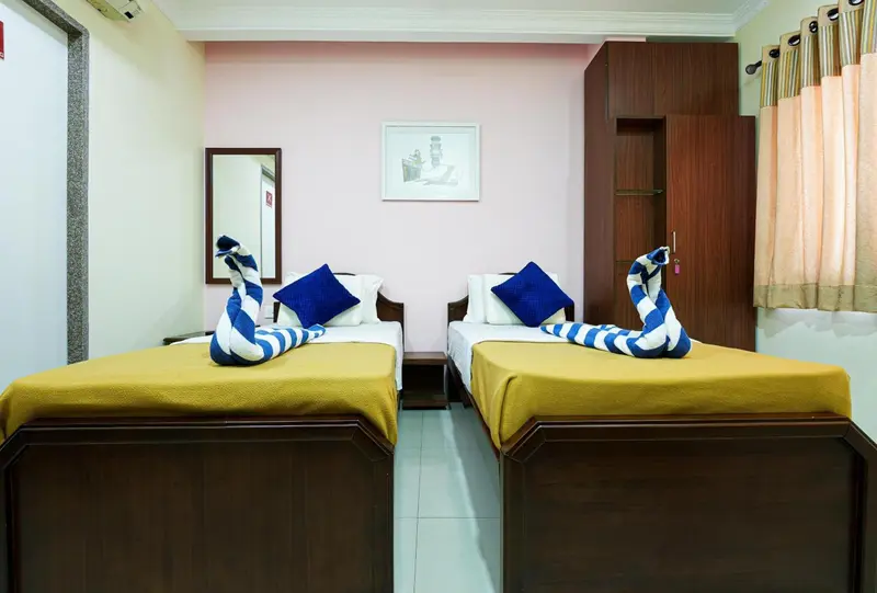 Deux lits simples avec des couvertures jaunes dans une chambre lumineuse.