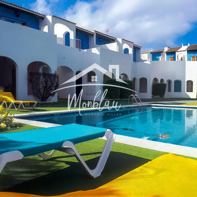 Transats bleus au bord d'une piscine turquoise devant un bâtiment blanc.