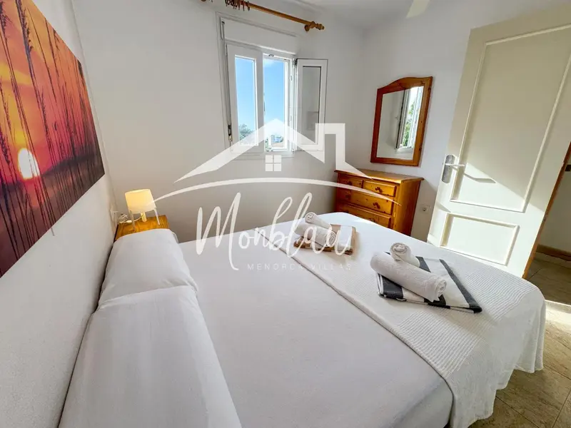 Une chambre lumineuse avec un grand lit et un tableau mural coloré.