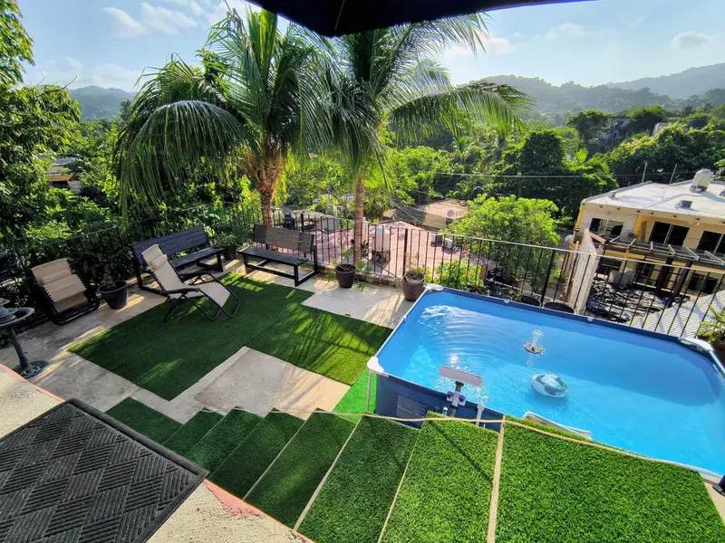 Terrasse avec piscine et mobilier de jardin offrant une vue sur la végétation luxuriante et les collines.
