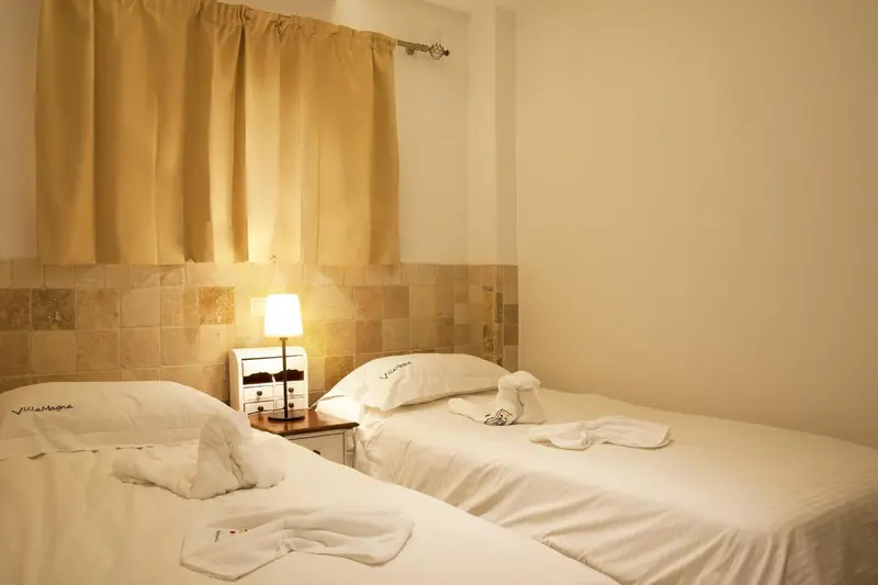 Une chambre lumineuse avec deux lits simples et une décoration murale en mosaïque.