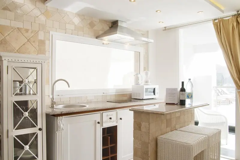 Une kitchenette lumineuse avec un évier, un micro-ondes et un comptoir bar.