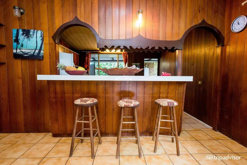 Un comptoir de bar en bois avec des tabourets hauts dans une ambiance chaleureuse.