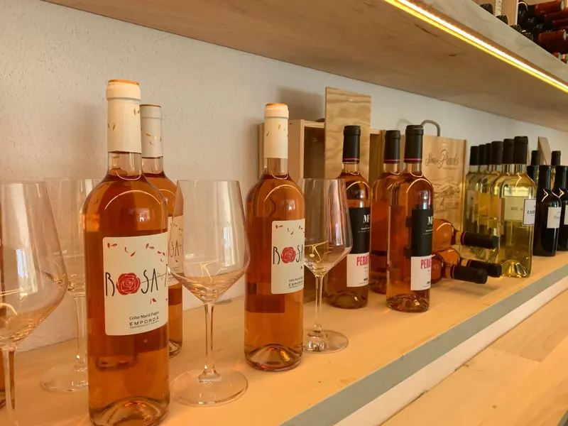 Des bouteilles de vin et des verres à vin sont alignés sur une étagère.
