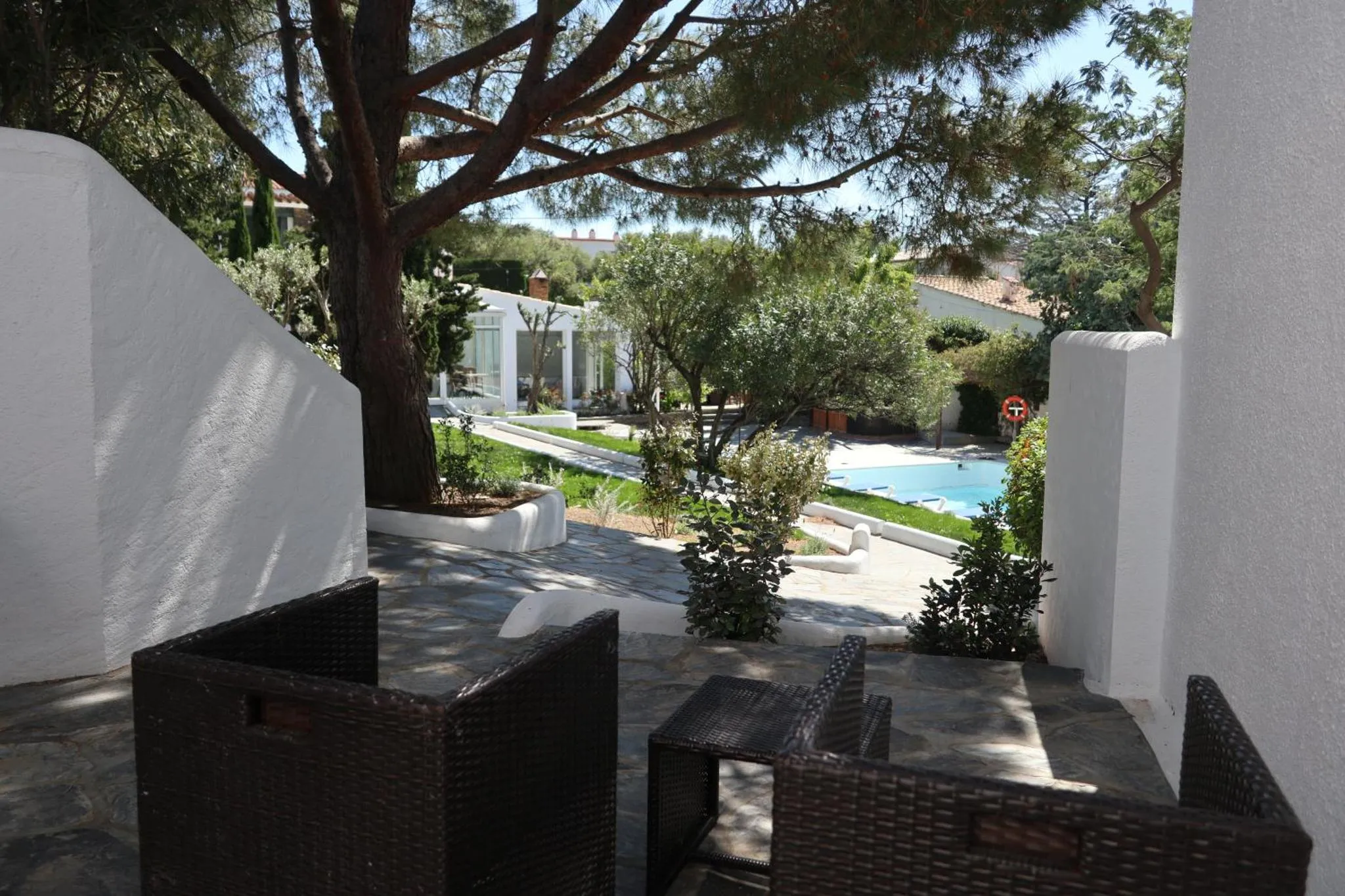 Terrasse ombragée donnant sur une piscine et un jardin soigné.