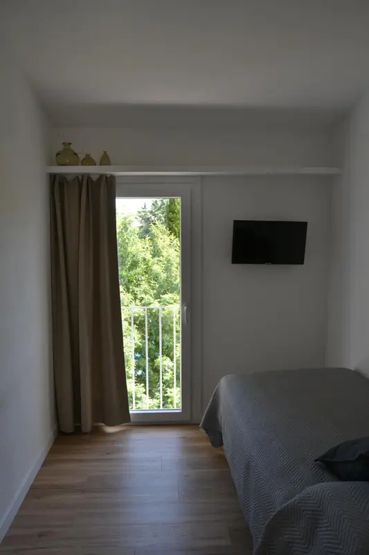 Une chambre lumineuse avec un lit et une vue sur la verdure.
