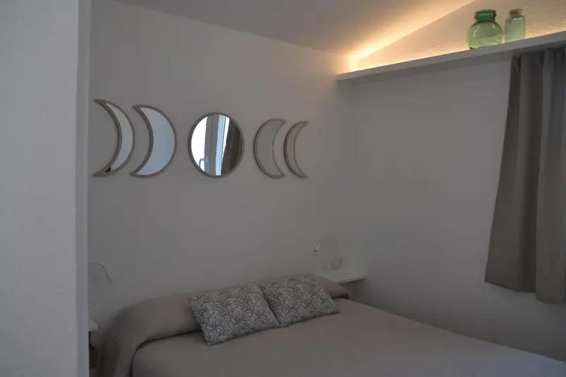 Une chambre lumineuse avec un lit et des miroirs décoratifs au mur.