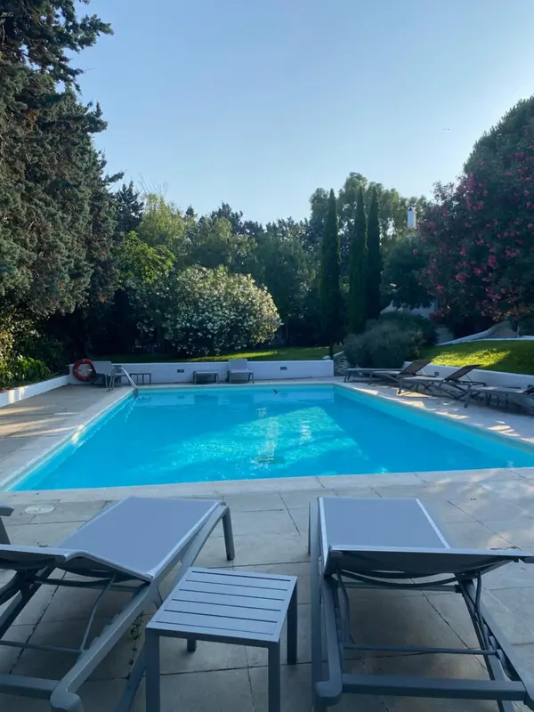 Une piscine rectangulaire entourée d'un sol carrelé et de chaises longues.