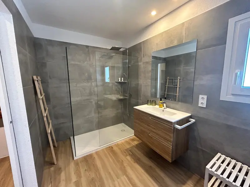 Une salle de bain moderne avec douche à l'italienne et vasque en bois.